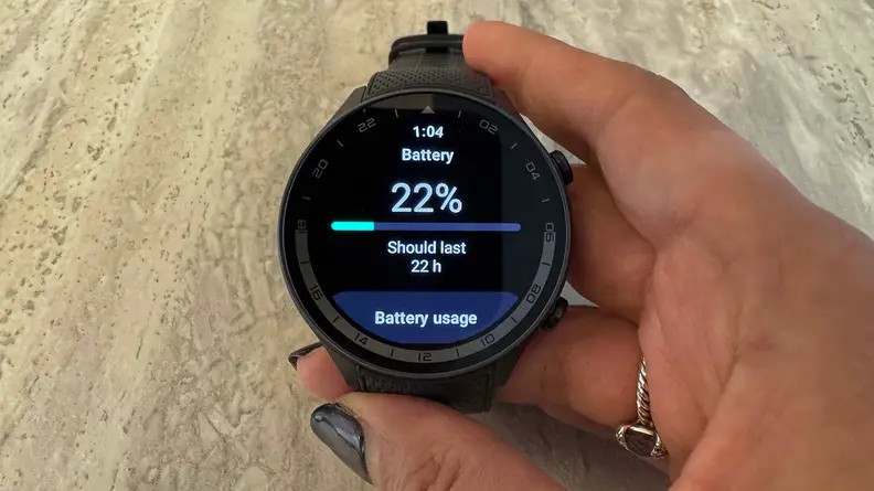 A hand holding the OnePlus Watch 2R, displaying 22% batery.