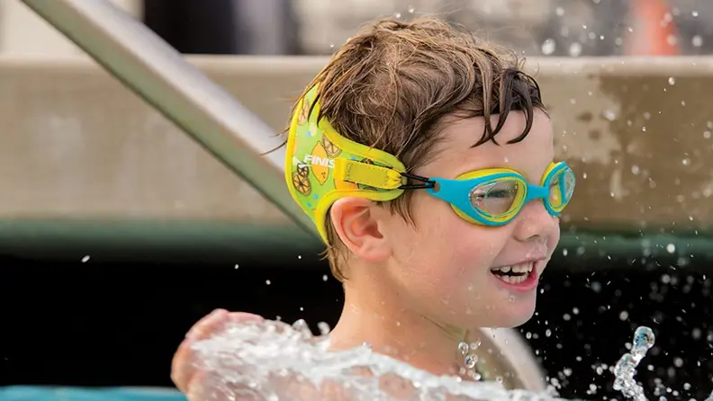 A boy smiles with his Finis swimming goggles on