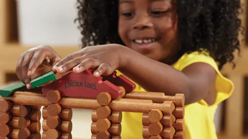 A girl smiles as she builds her Lincoln Logs