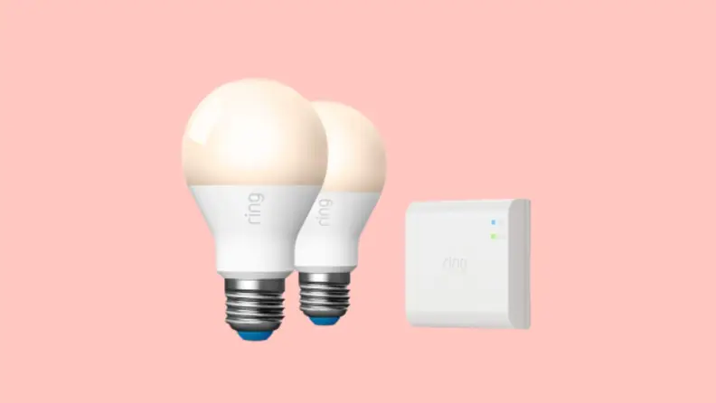 Two Ring smart bulbs and a Ring lighting bridge on a peach-colored background