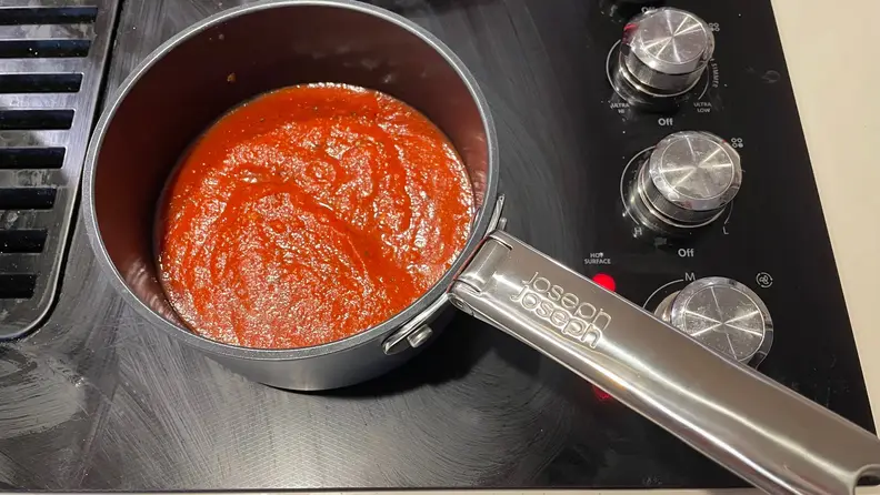 Red sauce cooking inside a pot.