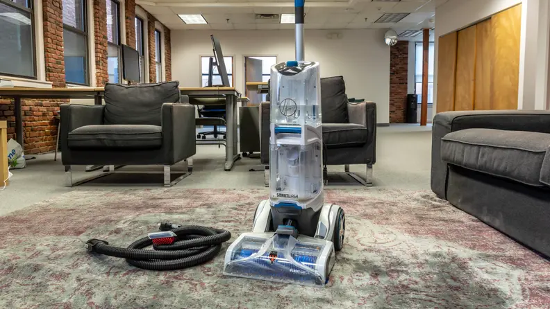 Carpet cleaner on a rug next to cleaning accessories