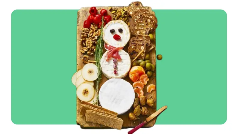 A cutting board with snacks making up a snowman.
