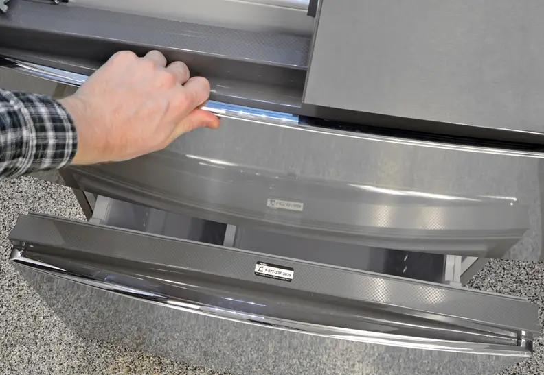 A hand reaches into frame to pull open the fridge's flex drawer.
