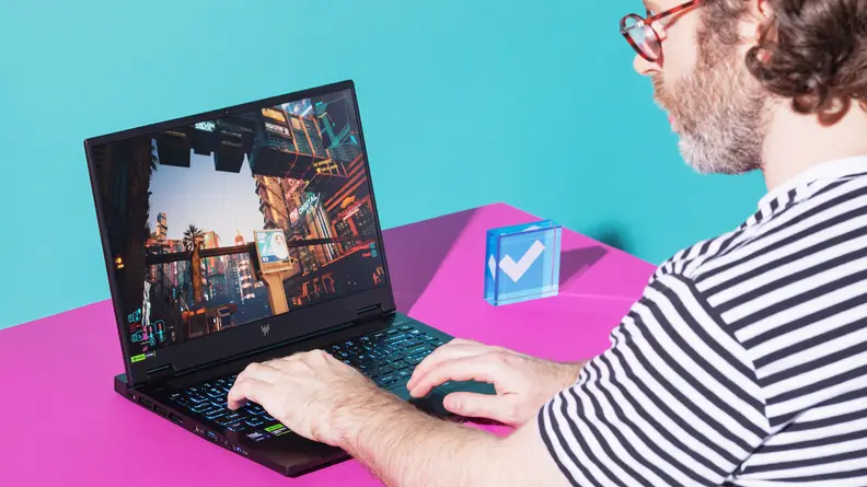 A man sitting in front of a Acer Predator Helios Neo 14 gaming laptop