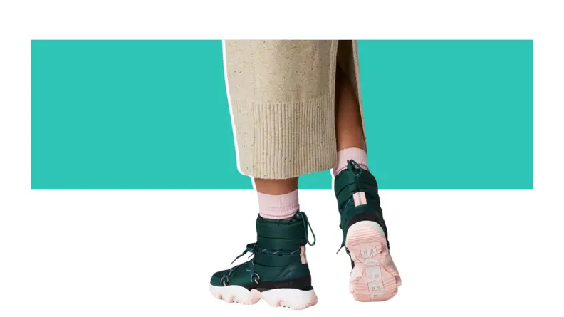 A model's legs -- they wear green puffy boots with pink accents.