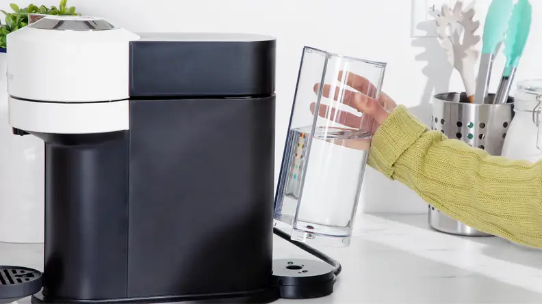 Person placing water reservoir chamber back into place on the back of the Nespresso Vertuo Next coffee maker.
