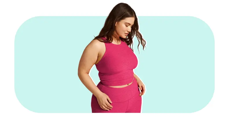 Model posing while wearing pink Beyond Yoga Refocus Cropped Tank and pants.