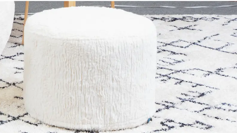 A close-up of Lovesac’s white furry ottoman.