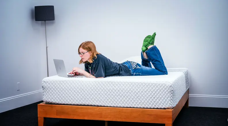 The Leesa Hybrid mattress sits in a room with a woman on it.