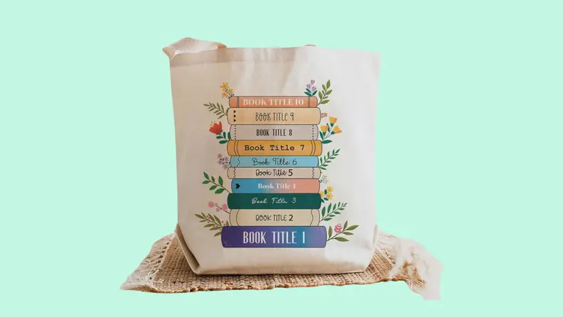 A white tote bag with colorful writing on it on a green background.