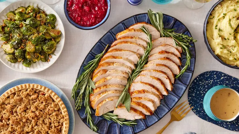 A sliced turkey surrounded by side dishes on a table