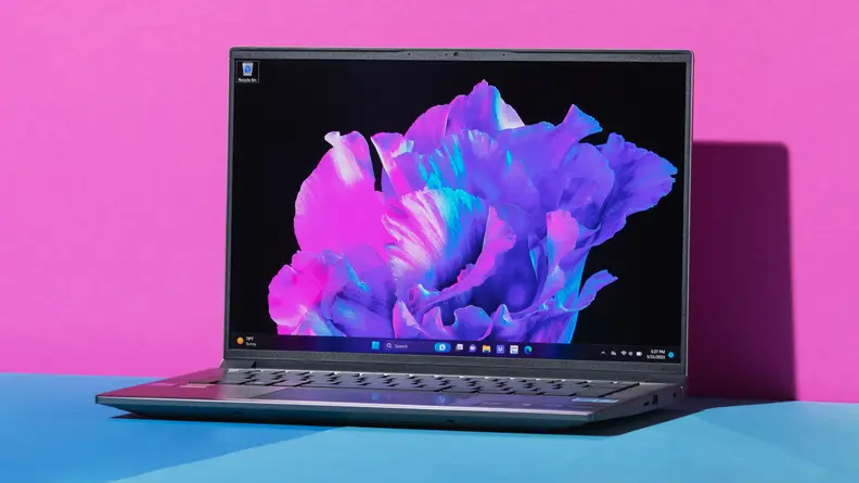 The Acer Swift X 14 laptop on a blue table with a pink background.