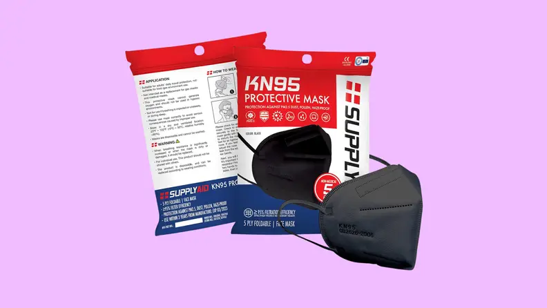 A black SupplyAID KN95 face mask next to its packaging on a purple background.