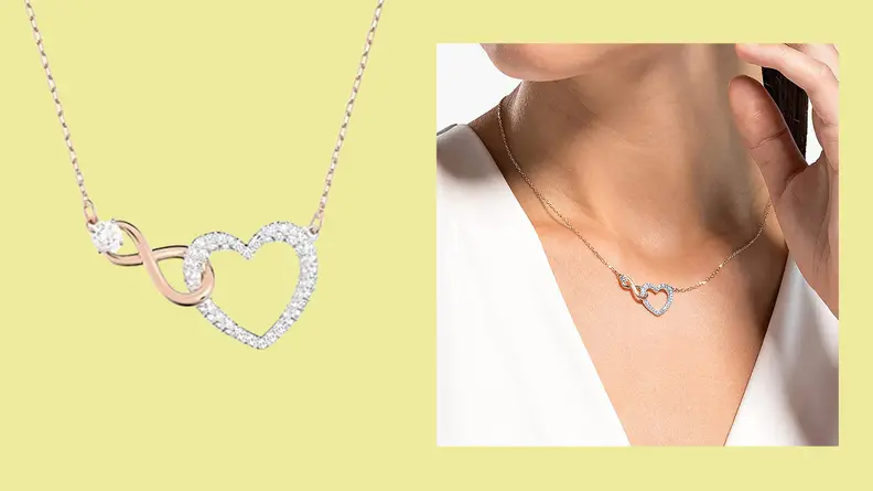 A closeup of aa necklace with an infinity symbol connected to a heart shape with small diamonds around the heart symbol.