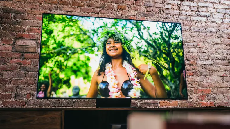 TV has limited borders around the screen and sits atop a curved metal stand centered beneath it