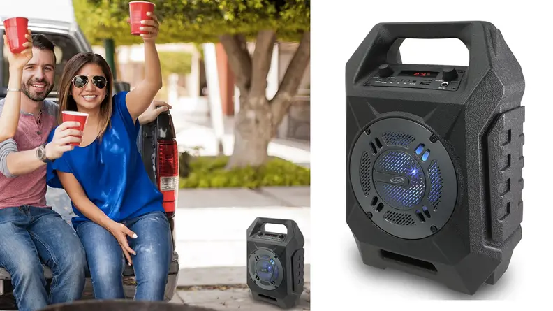 A group of people having drinks and leaning against a truck while listening to music from a large speaker
