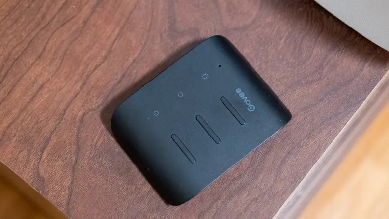 Black Govee remote shown on top of a brown wooden surface.