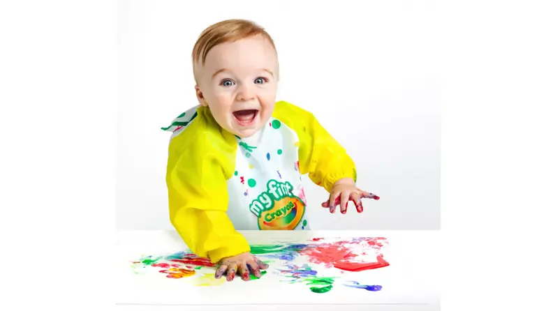 A toddler plays gleefully with finger paints.