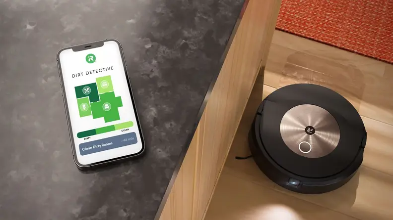 A smartphone on a gray countertop above a black and gold robot vacuum