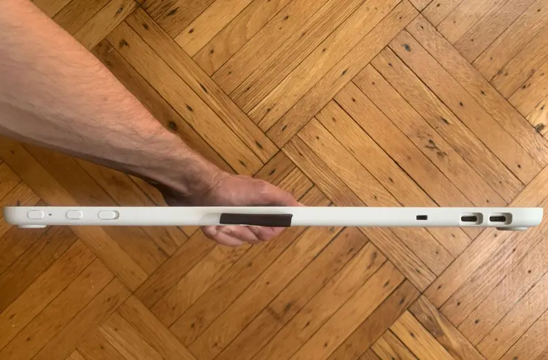 An arm holds the Wacom One over a wood floor, with its ports visible.