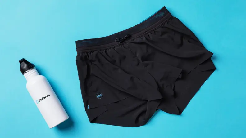 A pair of black Janji running shorts next to a white water bottle.