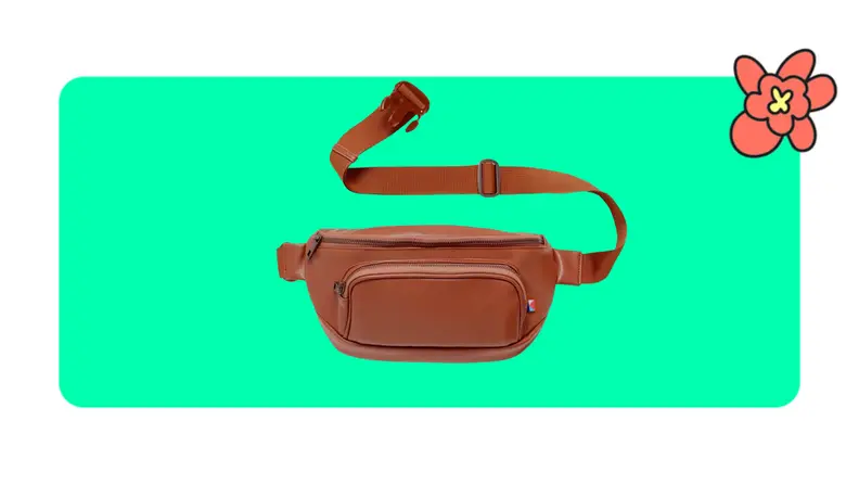 A tan faux leather Kibou fanny pack with extended strap in front of a green background with a red cartoon flower in the corner.