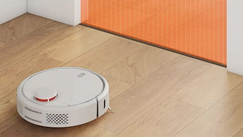 A robot vacuum on the floor close to a boundary marked by tape