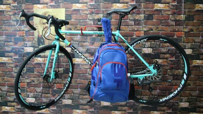 Bike on a bike wall mount with a backpack attached on a brick backdrop