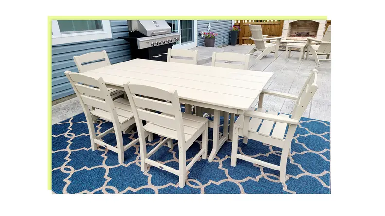 A white outdoor dining table and chair sits  outside on a patio.