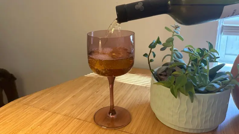 A purple wine glass being filled with wine.