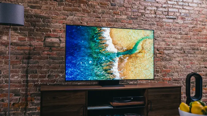 The TV sits on a table, showing a brilliantly blue-green ocean crashing onto a sandy beach