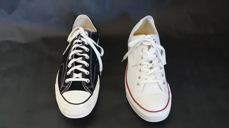 Black low top Chuck 70 next to a white low top Chuck Taylor All Star sneaker.