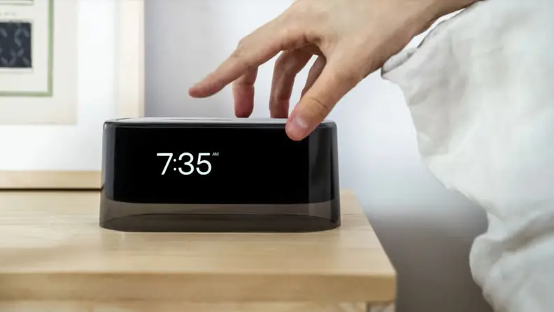 A hand reaches for the Loftie alarm clock, which says it's 7:35 a.m.