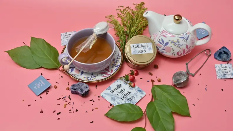 A tea set is surrounded by the herbs and ingredients that create the flavor profile of La Rue 1680's tea.