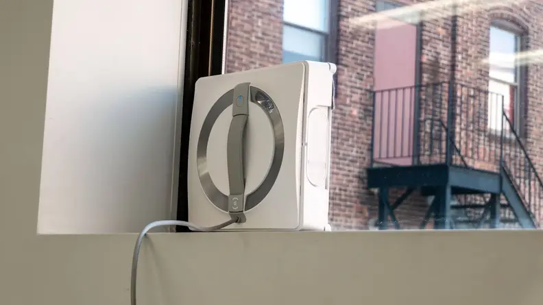 The Ecocovacs Winbot W2 Omni cleaning an interior window.