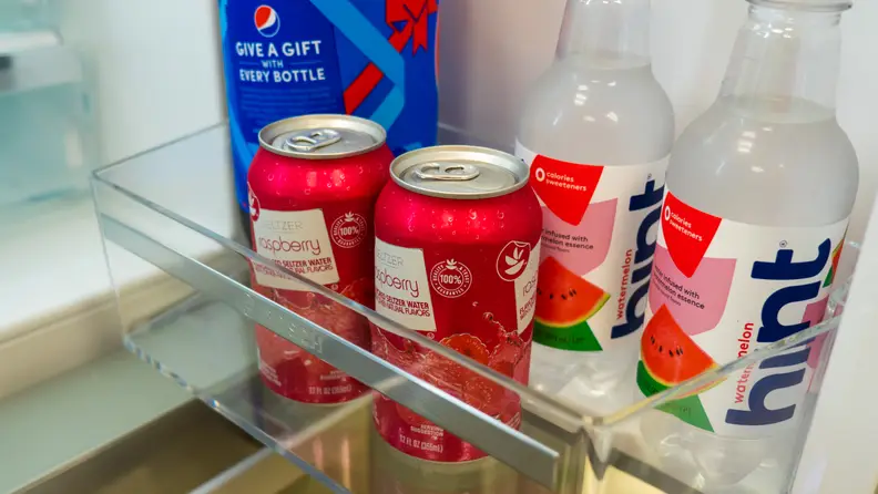 A close-up shot of the Bosch B36CD50SNS French-door refrigerator's door bins, with a couple cans of coke and bottles stored there for a sense of scale. The wall come up to about the center of the coke cans.