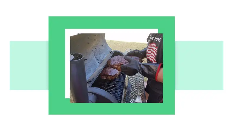 A man cooking on a grill wearing heat-resistant gloves.