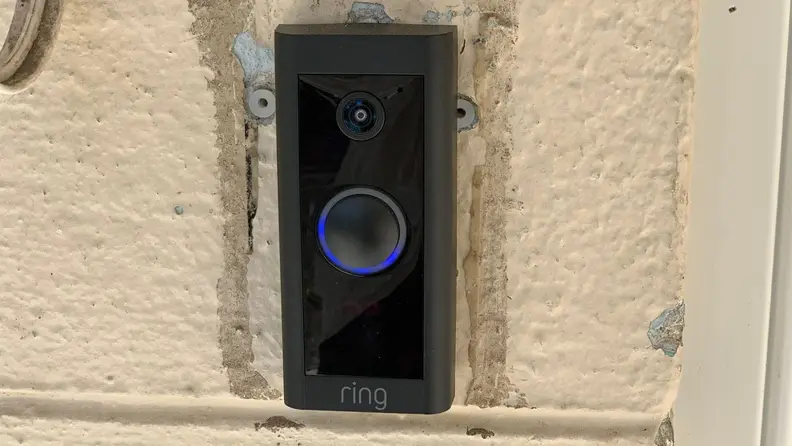 The Ring Video Doorbell installed on a cream door frame.