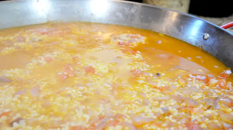Make sure to spread the rice evenly in the paella pan.