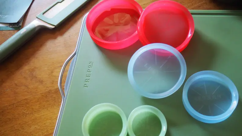 Silicone food  storage lids in red, blue and green on green chopping board