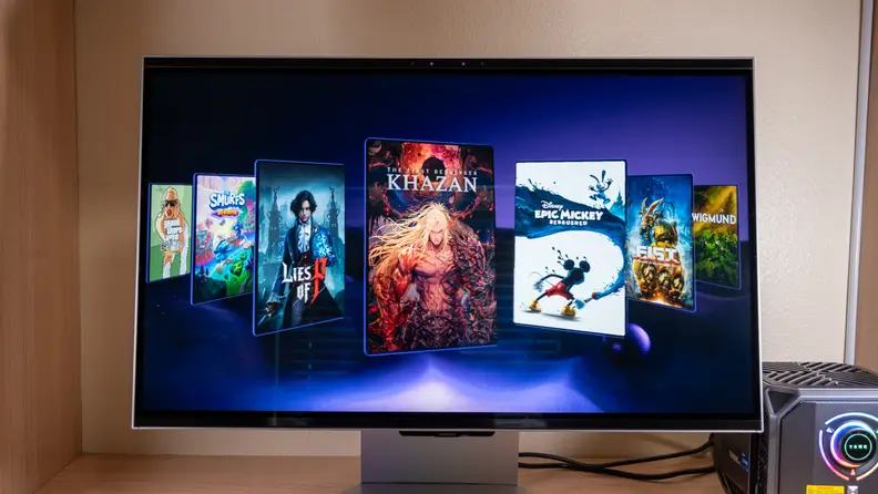 A large 3D gaming monitor sits on a desk with a gallery of video games on its screen