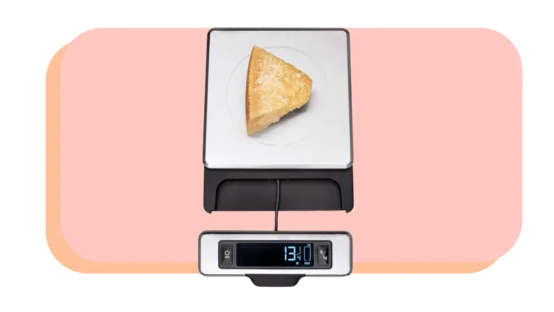 Wedge of cheese sitting on top food scale.