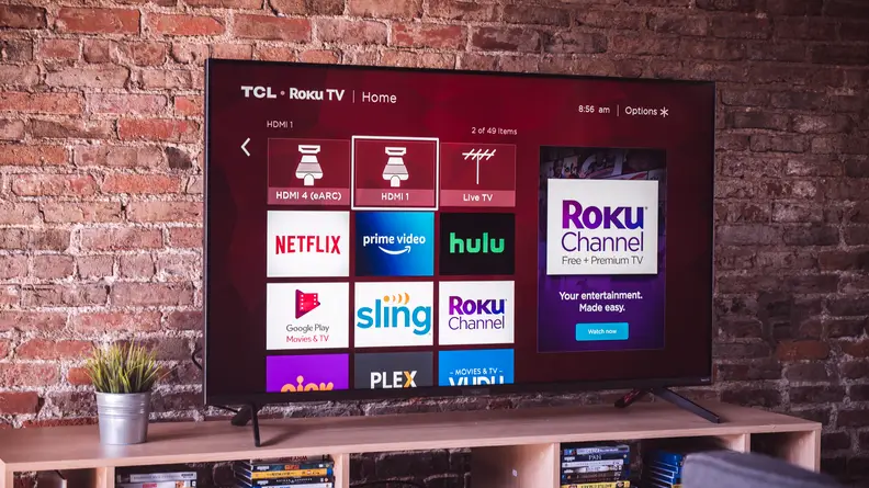 The 2020 TCL 6-Series displaying the Roku smart platform home screen in a living room setting