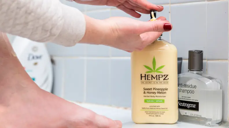 A person's hand pumping a bottle of Hempz Moisturizing Skin body lotion.