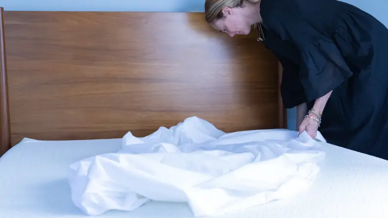 A woman putting a mattress cover on a 5 Little Monkeys mattress.