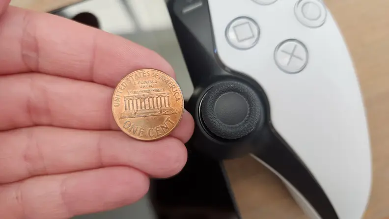 A side by side size comparison of the PlayStation Portal thumbstick pads and a penny.