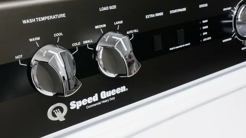A close-up of the wash load and temperature control dials on the Speed Queen TR5000WN AWN63RSN115TW01 top-loading washer's control panel.