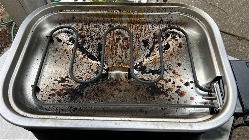 The inside of the Weber Lumin grill completely dirty.