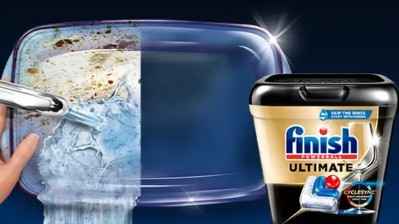 A creative image of a glass casserole dish, where half is being washed in the sink with faucet on, and the other half is sparkly clean. On its right is Finish dishwasher pod.